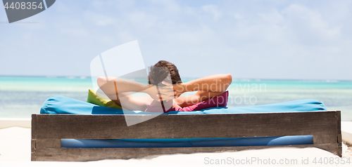 Image of Relaxed man in luxury lounger enjoying summer vacations on beautiful beach.