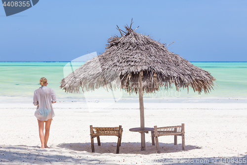 Image of Lady walking to the sea oat white sandy tropical beach of Paje, Zanzibar, Tanzania.