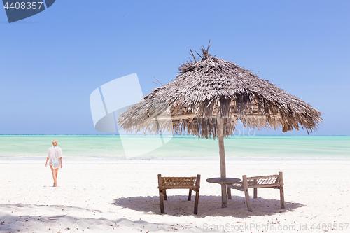 Image of Lady walking to the sea oat white sandy tropical beach of Paje, Zanzibar, Tanzania.