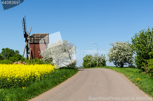 Image of Country road by an old windmill in a colorful spring season land