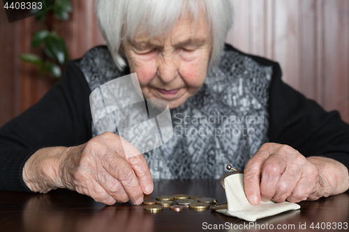 Image of Elderly woman sitting at the table counting money in her wallet.