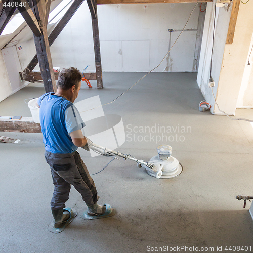 Image of Laborer polishing sand and cement screed floor.