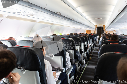 Image of Interior of large commercial airplane with passengers on their seats during flight.