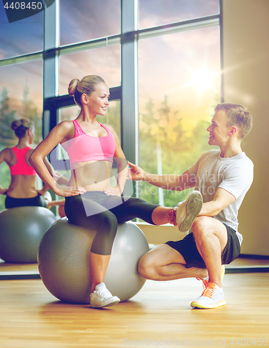 Image of smiling man and woman with exercise ball in gym