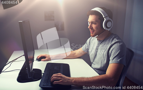 Image of man in headset playing computer video game at home