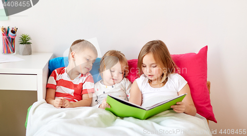 Image of little kids reading book in bed at home