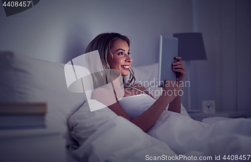 Image of young woman with tablet pc in bed at home bedroom