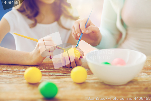 Image of daughter and mother coloring easter eggs
