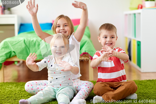 Image of group of happy kids sitting on floor at home