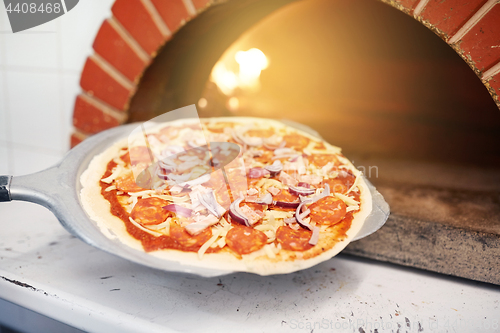 Image of peel placing pizza into oven at pizzeria