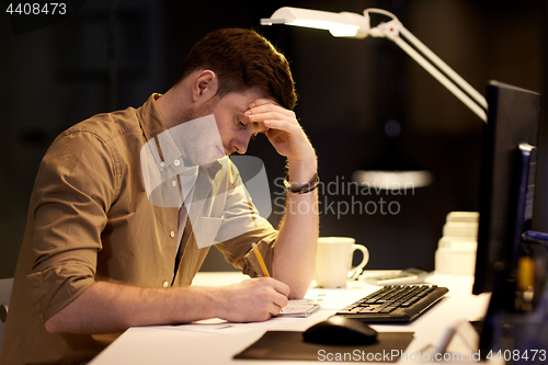 Image of man with notepad working late at night office