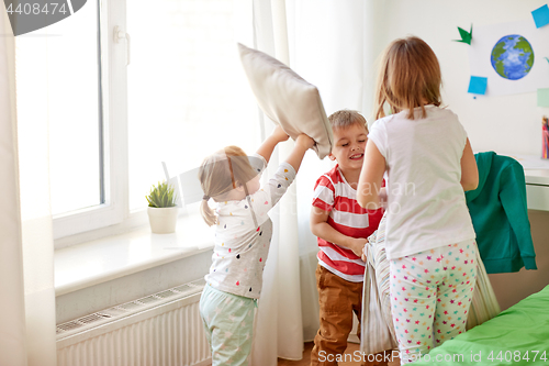 Image of kids playing and fighting by pillows at home