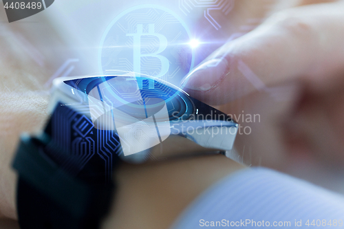 Image of close up of hands with bitcoin on smart watch