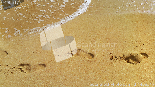 Image of Sea water and footprints in the sand at the beach