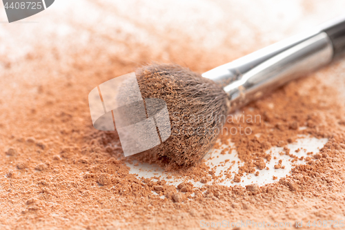 Image of Close-up of crushed mineral shimmer powder golden color with makeup brush