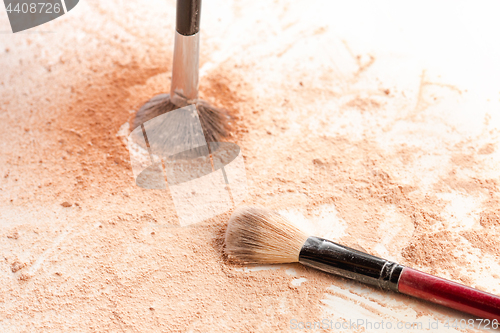 Image of Close-up of crushed mineral shimmer powder golden color with makeup brush