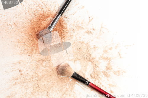 Image of Close-up of crushed mineral shimmer powder golden color with makeup brush