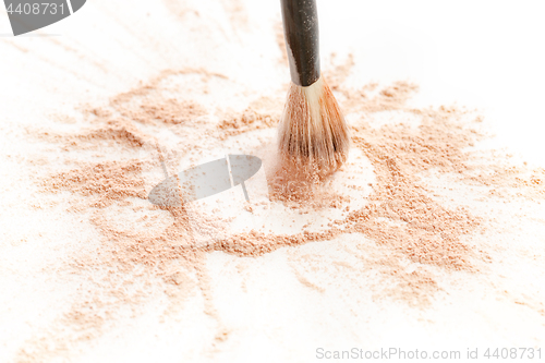 Image of Close-up of crushed mineral shimmer powder golden color with makeup brush