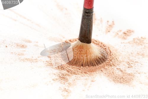 Image of Close-up of crushed mineral shimmer powder golden color with makeup brush