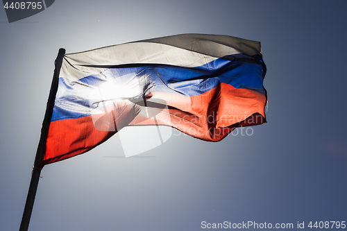 Image of russian flag flying in slow motion and back lit by the sun.