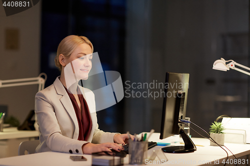 Image of businesswoman at computer working at night office