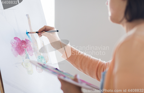 Image of artist with palette and brush painting at studio