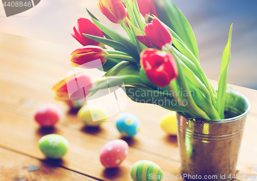 Image of tulip flowers in bucket and easter eggs on table