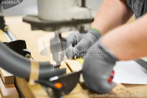 Image of carpenter with ruler measuring board at workshop