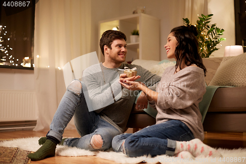 Image of happy couple with gift box at home