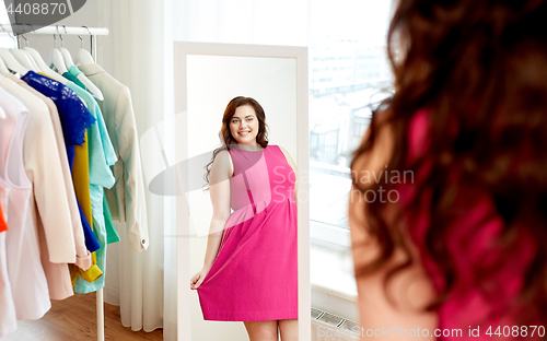 Image of happy plus size woman in dress looking at mirror