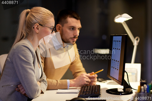 Image of business team with computer working late at office