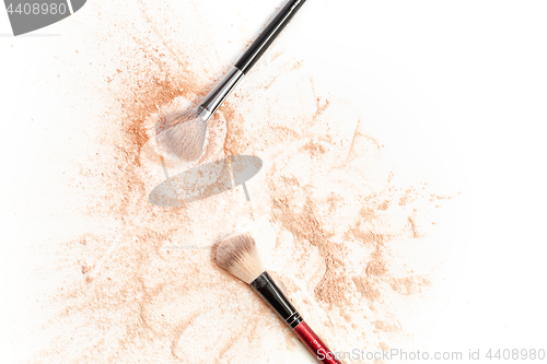 Image of Close-up of crushed mineral shimmer powder golden color with makeup brush