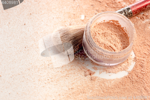 Image of Close-up of crushed mineral shimmer powder golden color with makeup brush