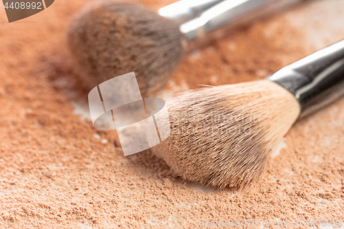 Image of Close-up of crushed mineral shimmer powder golden color with makeup brush