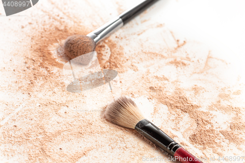 Image of Close-up of crushed mineral shimmer powder golden color with makeup brush