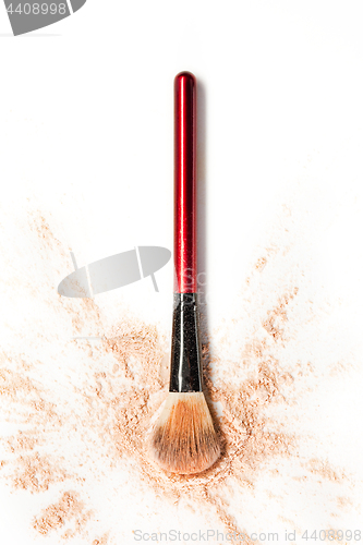 Image of Close-up of crushed mineral shimmer powder golden color with makeup brush