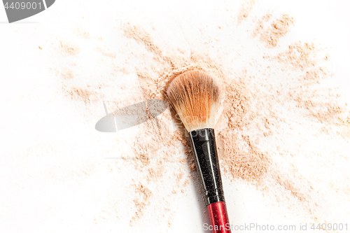 Image of Close-up of crushed mineral shimmer powder golden color with makeup brush