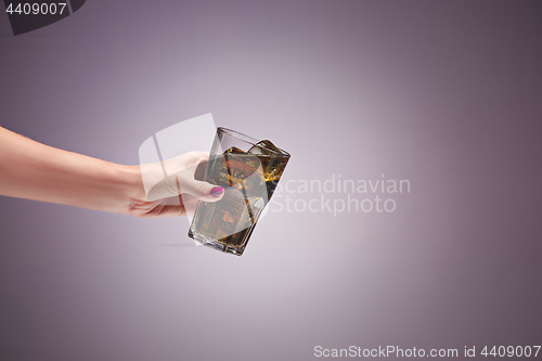 Image of Drink cola in glass with hand on lilac background.