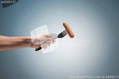 Image of sausage on a fork in his hand