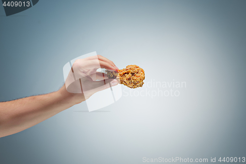 Image of A young man is holding a roasted chicken drumstick