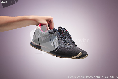 Image of Hand Holding An Old Dirty Sneaker Shoe