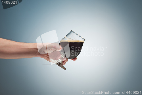 Image of Closeup of a male hand holding up a glass of beer