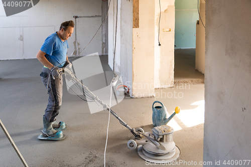 Image of Laborer polishing sand and cement screed floor.