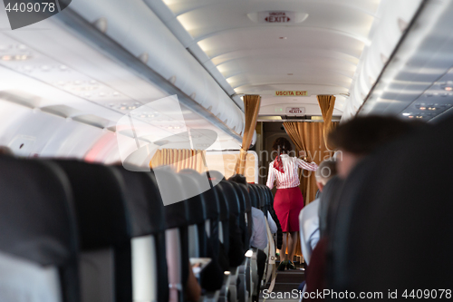 Image of Interior of commercial airplane with stewardess walking the aisle.