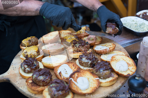 Image of Chef making beef burgers outdoor on open kitchen international food festival event.