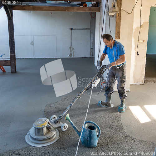 Image of Laborer polishing sand and cement screed floor.