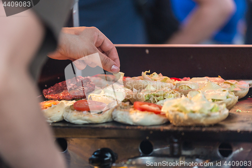 Image of Chef making beef burgers outdoor on open kitchen international food festival event.