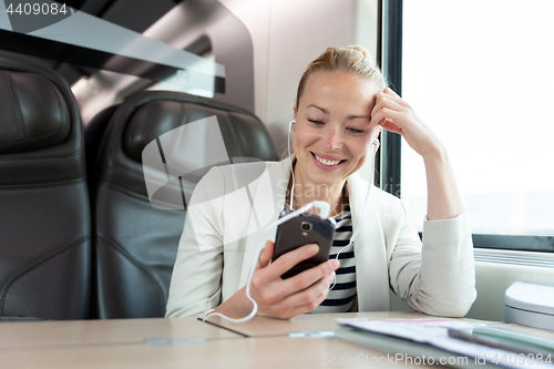 Image of Businesswoman communicating on mobile phone while traveling by train.