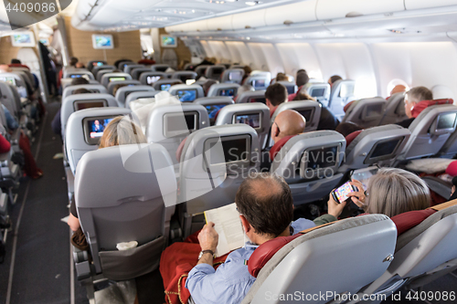 Image of Interior of large commercial airplane with passengers on their seats during flight.