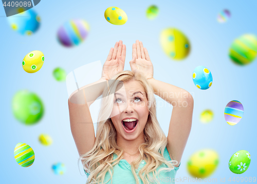 Image of happy woman making bunny ears over easter eggs